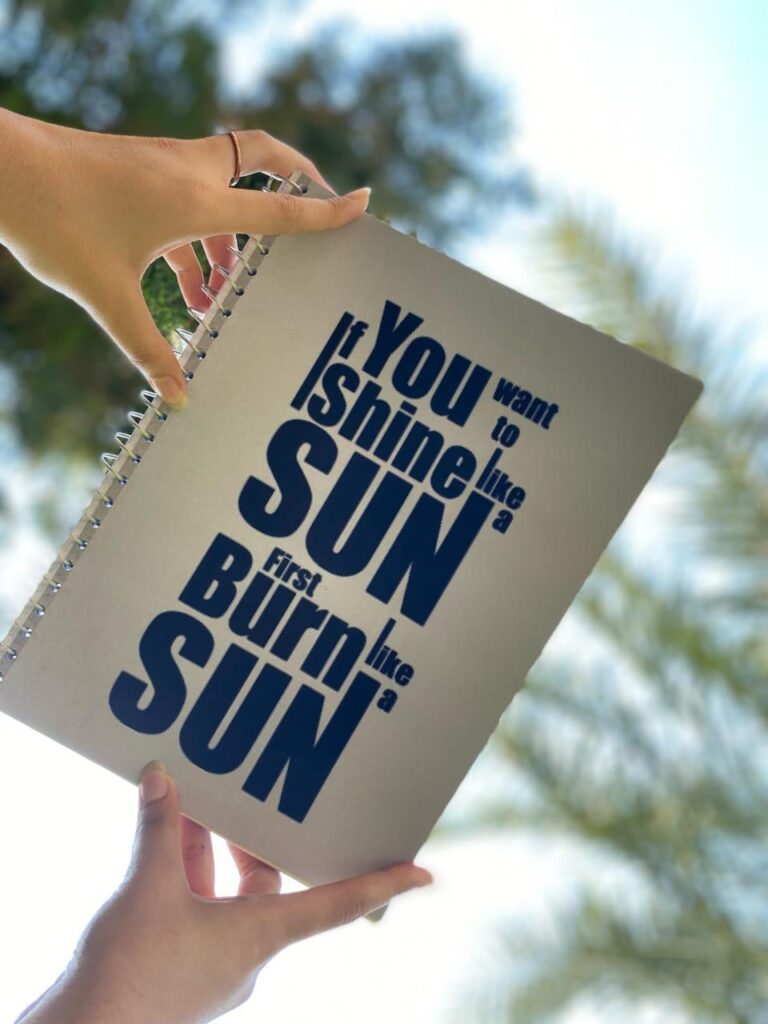 A custom spiral notebook titled "Radiance" featuring a sun-inspired motivational quote.
