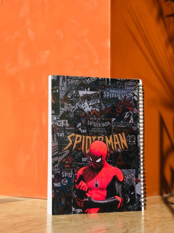 A spiral-bound notebook with a dense collage of vintage Spider-Man comic book covers in the background and a modern, high-detail Spider-Man figure in his red and black suit in the foreground.