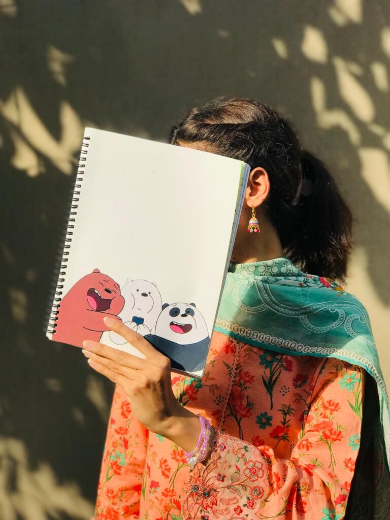 A clean white spiral notebook featuring Grizz, Ice Bear, and Panda from We Bare Bears laughing and posing together at the bottom left corner.